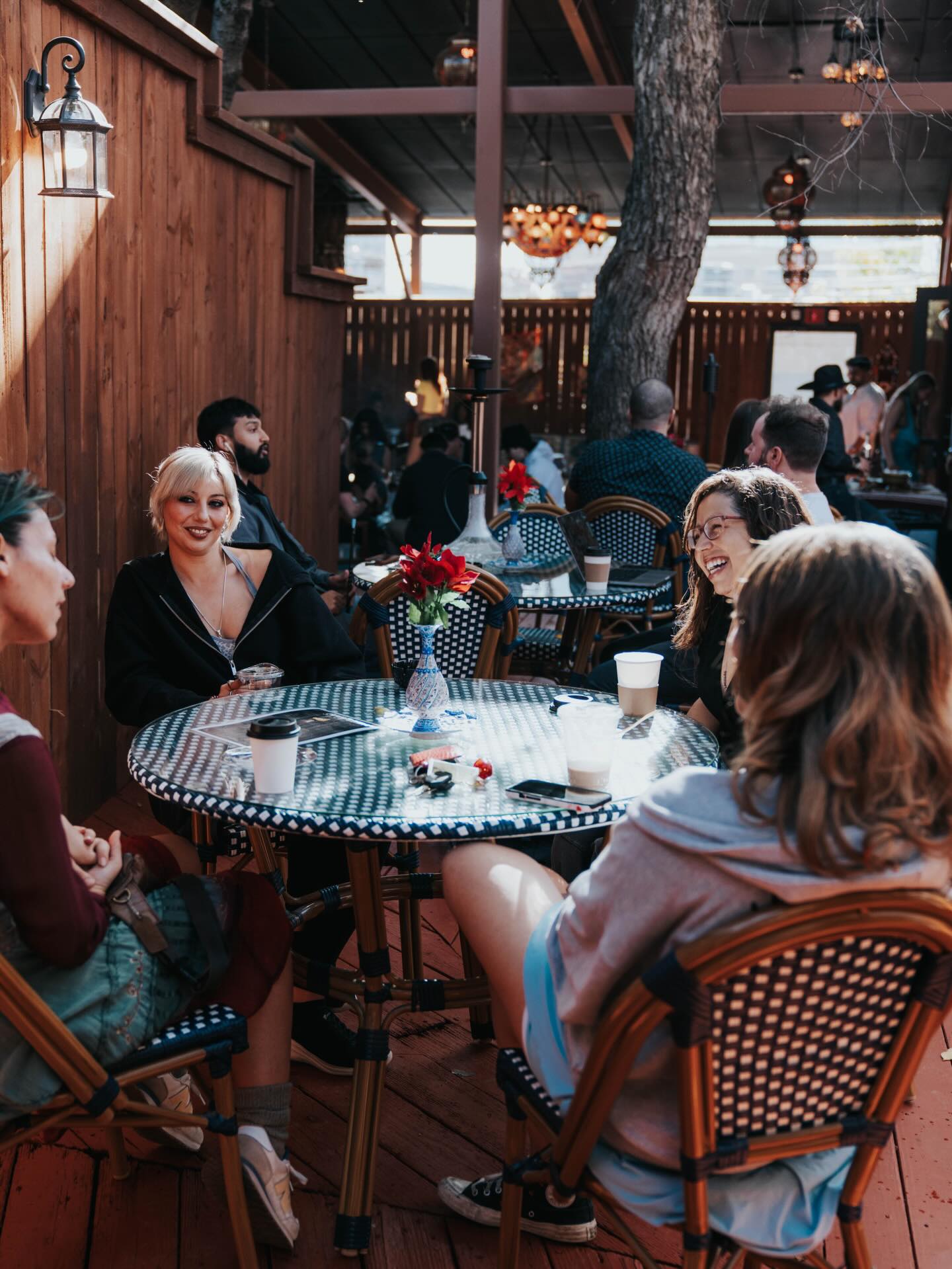 Friends sharing coffee around a mosaic patio table at Sip Haus Austin