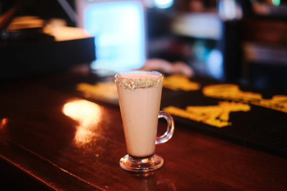 Hot latte in a glass mug with a pistachio rim