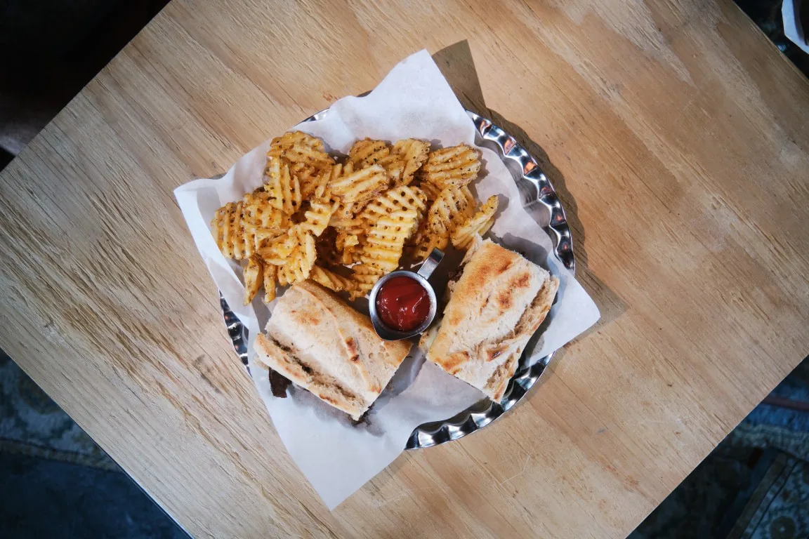 Overhead view of the Sip Haus Philly Cheesesteak with waffle fries