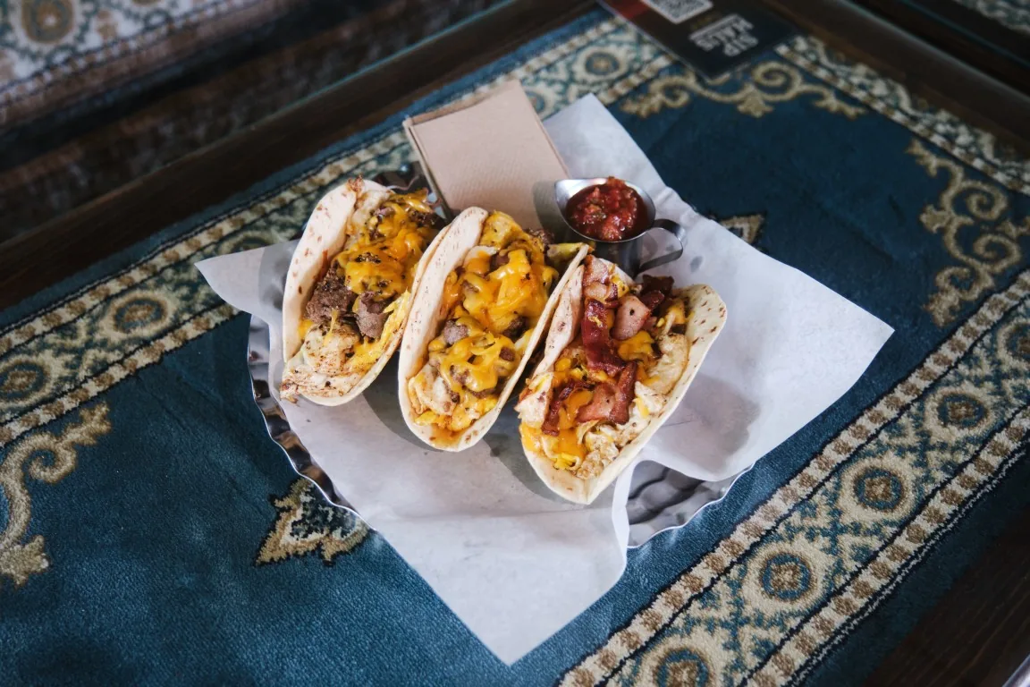 Three Sip Haus breakfast tacos with salsa on a Persian rug table