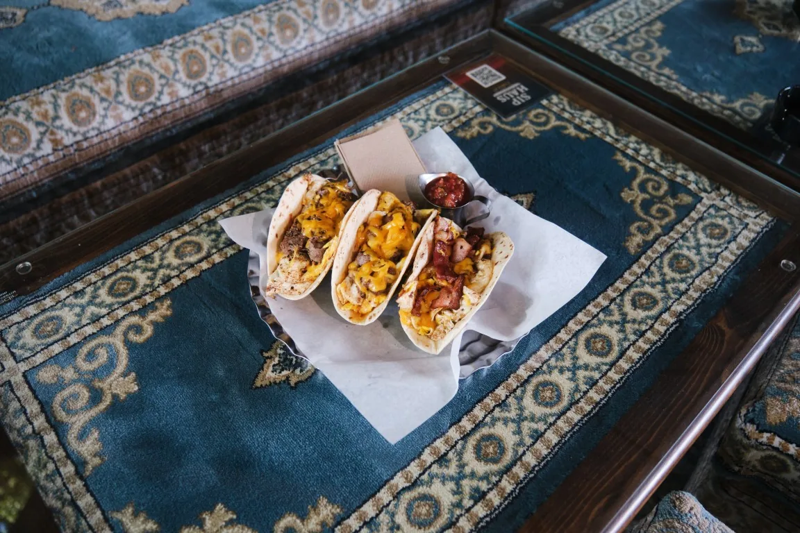 Breakfast tacos in a basket on a Persian rug table at Sip Haus