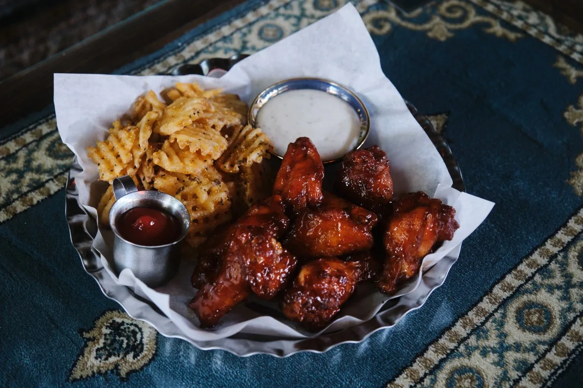 Sip Haus wings in glaze with waffle fries, ranch and ketchup on a Persian rug